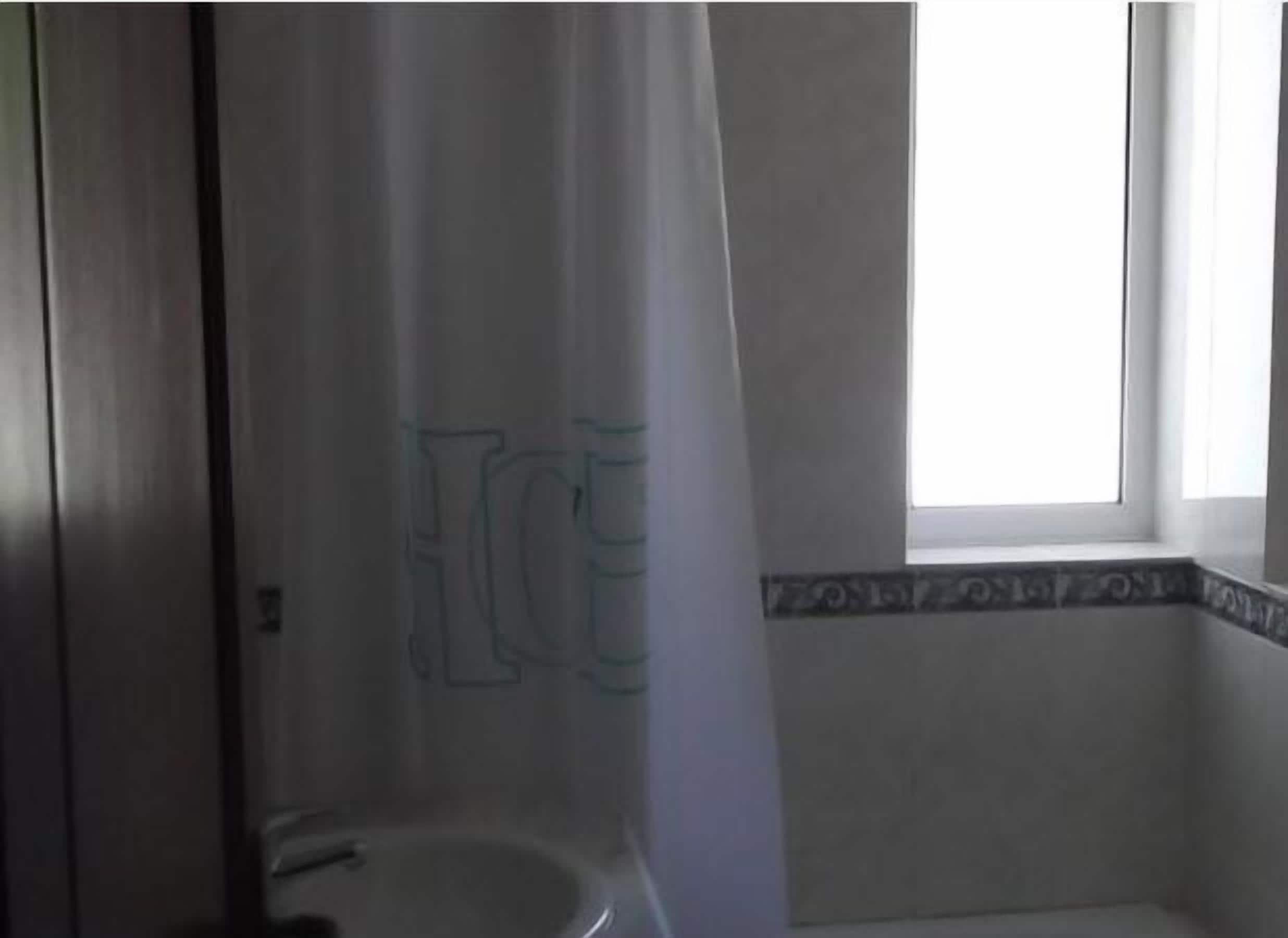 Un baño con inodoro, cortina de ducha y ventana.
