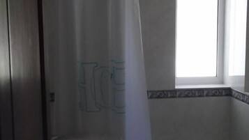 Un baño con inodoro, cortina de ducha y ventana.
