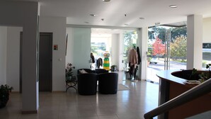 Un vestíbulo moderno con mostrador de recepción, zona de estar y grandes ventanales con vistas al exterior.
