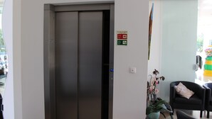 Un ascensor en el vestíbulo de un hotel con un cartel que indica los procedimientos de emergencia.