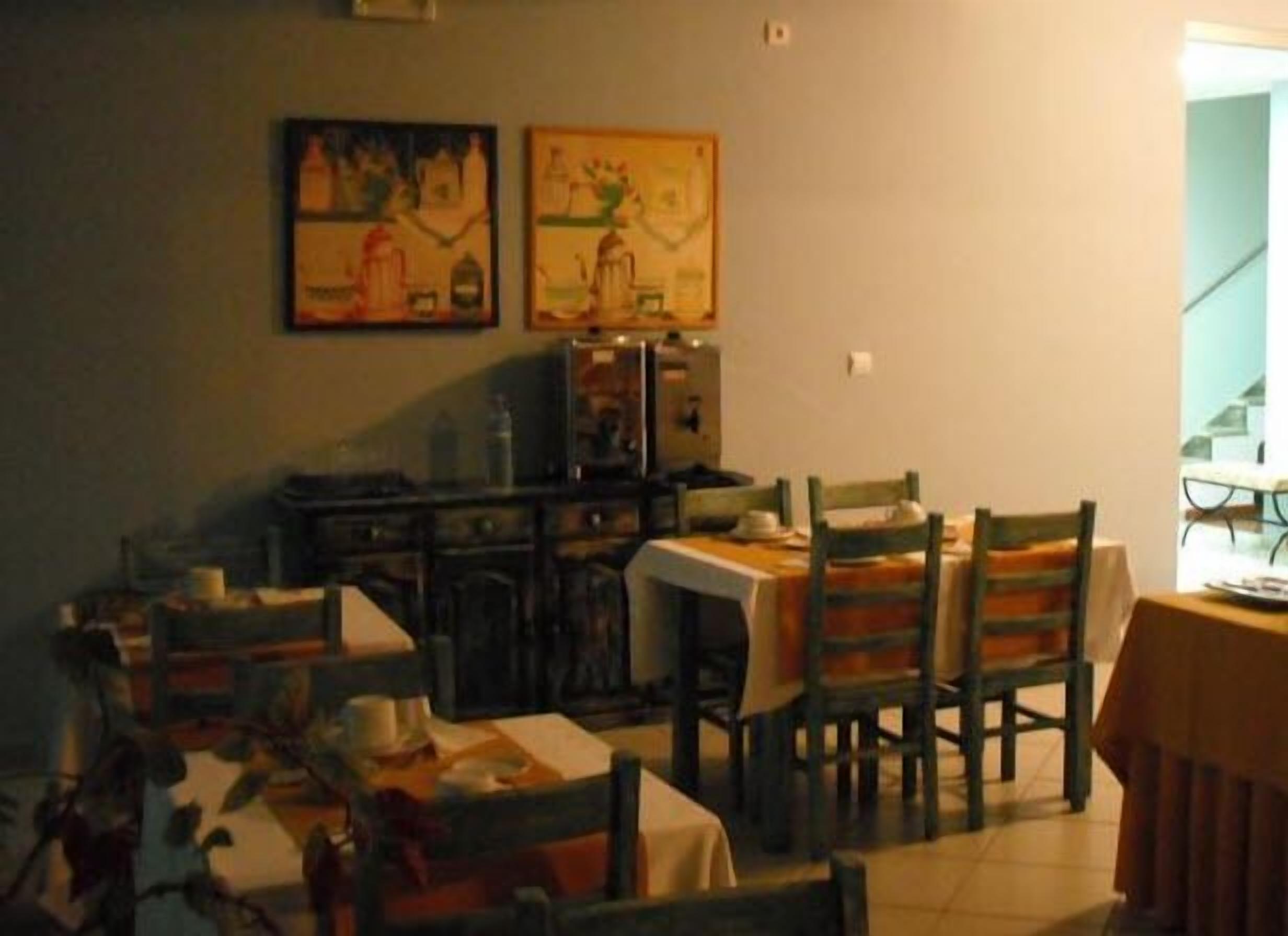 A dining area with a table set for four, wooden chairs, and two framed artworks on the wall.