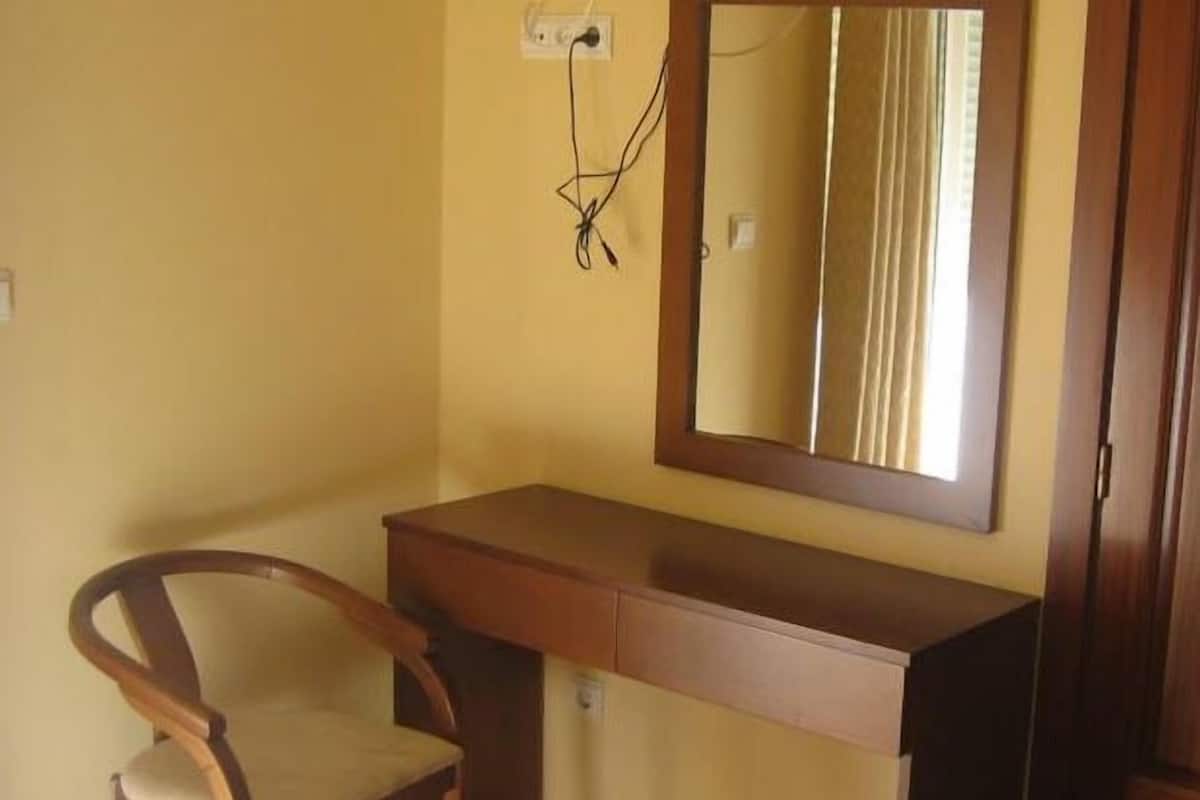 A small room with a wooden desk, a chair, and a mirror.