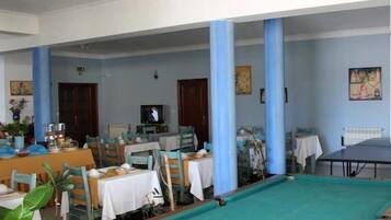 Un comedor con mesas y sillas, una mesa de billar y un televisor.