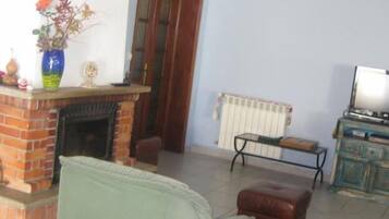 Una sala de estar con chimenea de ladrillo, un sofá, una mesita y un radiador.