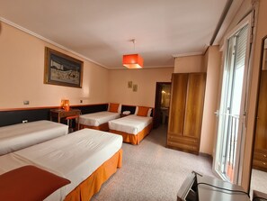 Habitación de hotel con dos camas individuales, un escritorio, una silla, un armario y un ventanal grande.