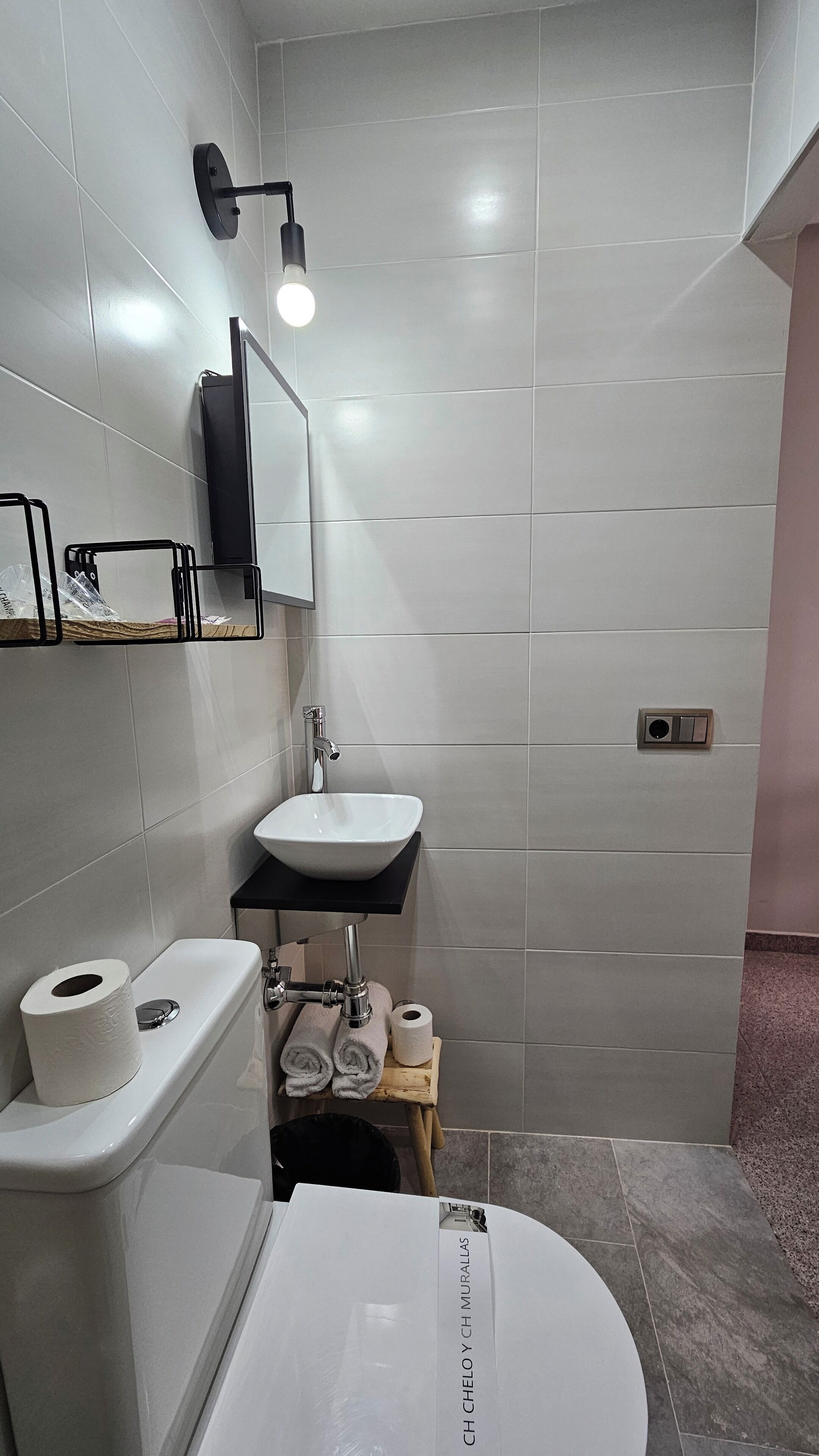 Un baño moderno con inodoro, lavamanos y zona de ducha.