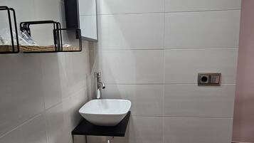 Un baño moderno con inodoro, lavamanos y zona de ducha.