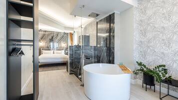 Un baño moderno con una bañera blanca grande, cabina de ducha de vidrio y pared de mármol.