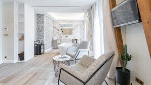 A modern living room with a sofa, a coffee table, and a cactus plant. - Le Dortoir Boutique Suites (Nice)