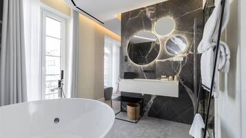 A modern bathroom with a freestanding bathtub, a marble vanity, and a large mirror with circular cutouts.