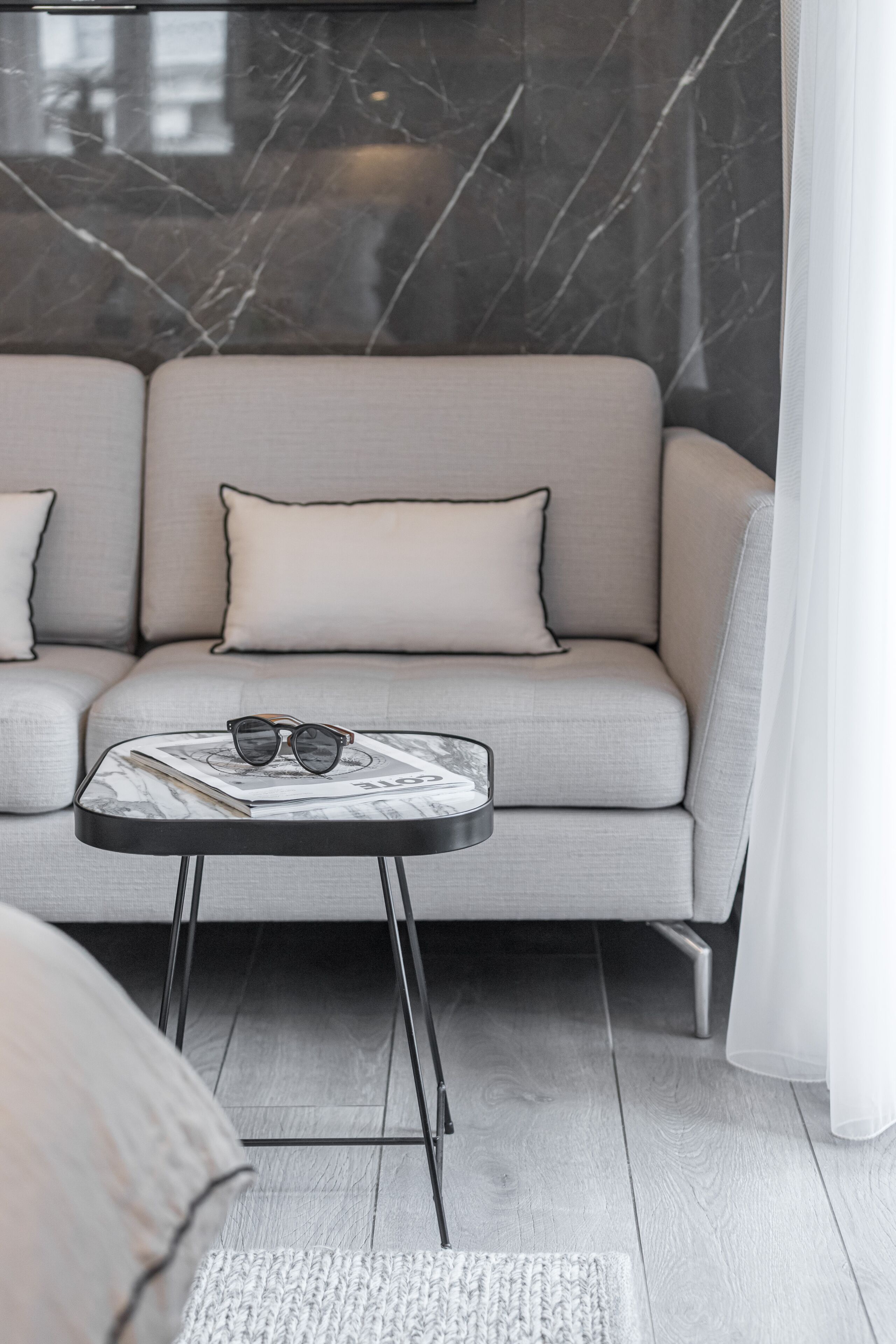 A modern living room with a sofa, a small round table, and a pair of glasses on the table.