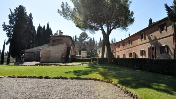 A building with a stone facade, a large tree in front, and a well-maintained lawn. - Tenuta la Campana (Asciano)