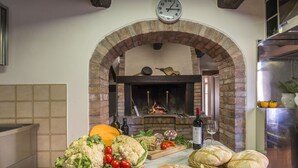 A kitchen with an arched brick fireplace, a clock, and various food items on the counter. - Tenuta la Campana (Asciano)