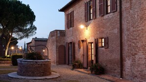 A traditional brick building with a circular stone fountain, wooden shutters, and a well-maintained garden. - Tenuta la Campana (Asciano)