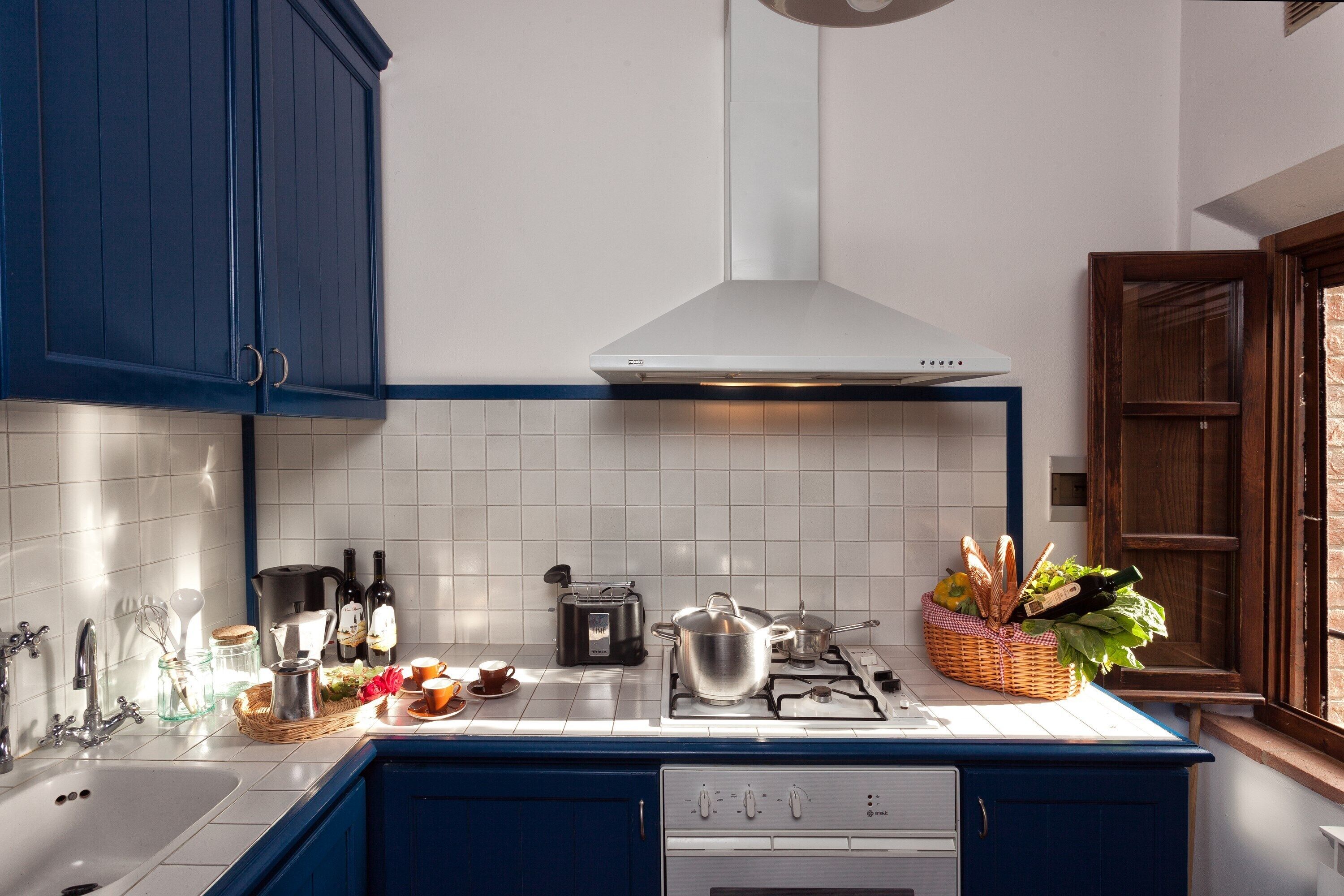 A kitchen with a stove, toaster, and various kitchen items on the counter.