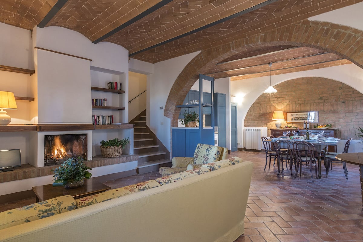 A cozy living room with a fireplace, a sofa, and a dining area with a table and chairs.