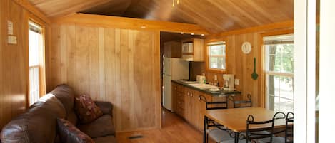 Un intérieur en bois comprenant un canapé, une table à manger, des chaises et un coin cuisine.