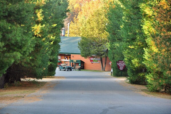 A campground entrance with a red building, a signboard, and a golf cart.