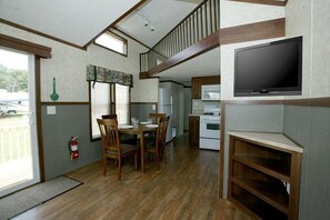 A compact kitchen with a built-in stove, a microwave, and a large TV.