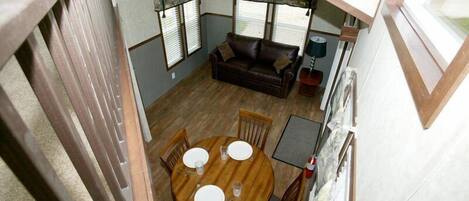 A compact living space with a round wooden dining table, a brown leather sofa, and a small side table.