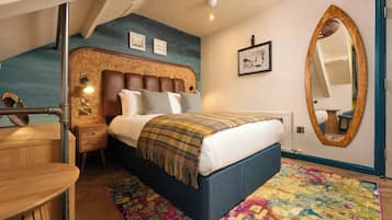 A bedroom with a bed, bedside tables, a mirror, and a colorful rug.