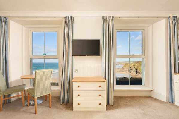 A room with a bay window, a television, a small wooden table, two chairs, and a white dresser. - Great Western Hotel (Newquay)