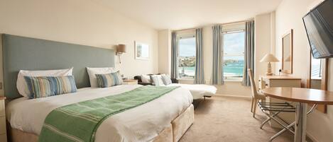 A hotel room with a large bed, a desk, and a TV.