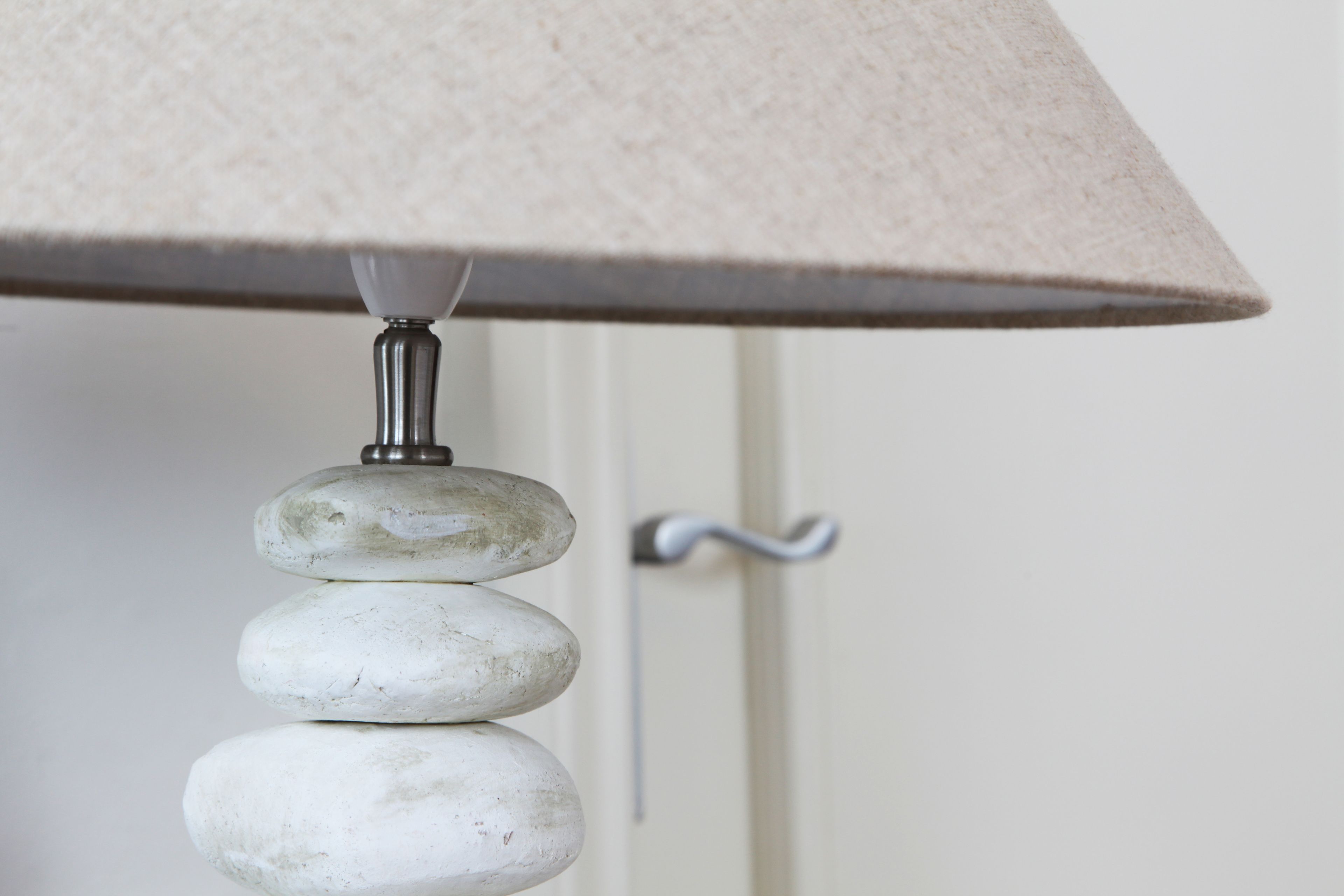 A lamp with a beige lampshade and a metal base.