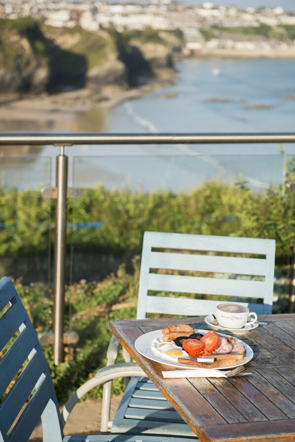 Mesa con un plato de comida y una taza, con vistas a un río y follaje.