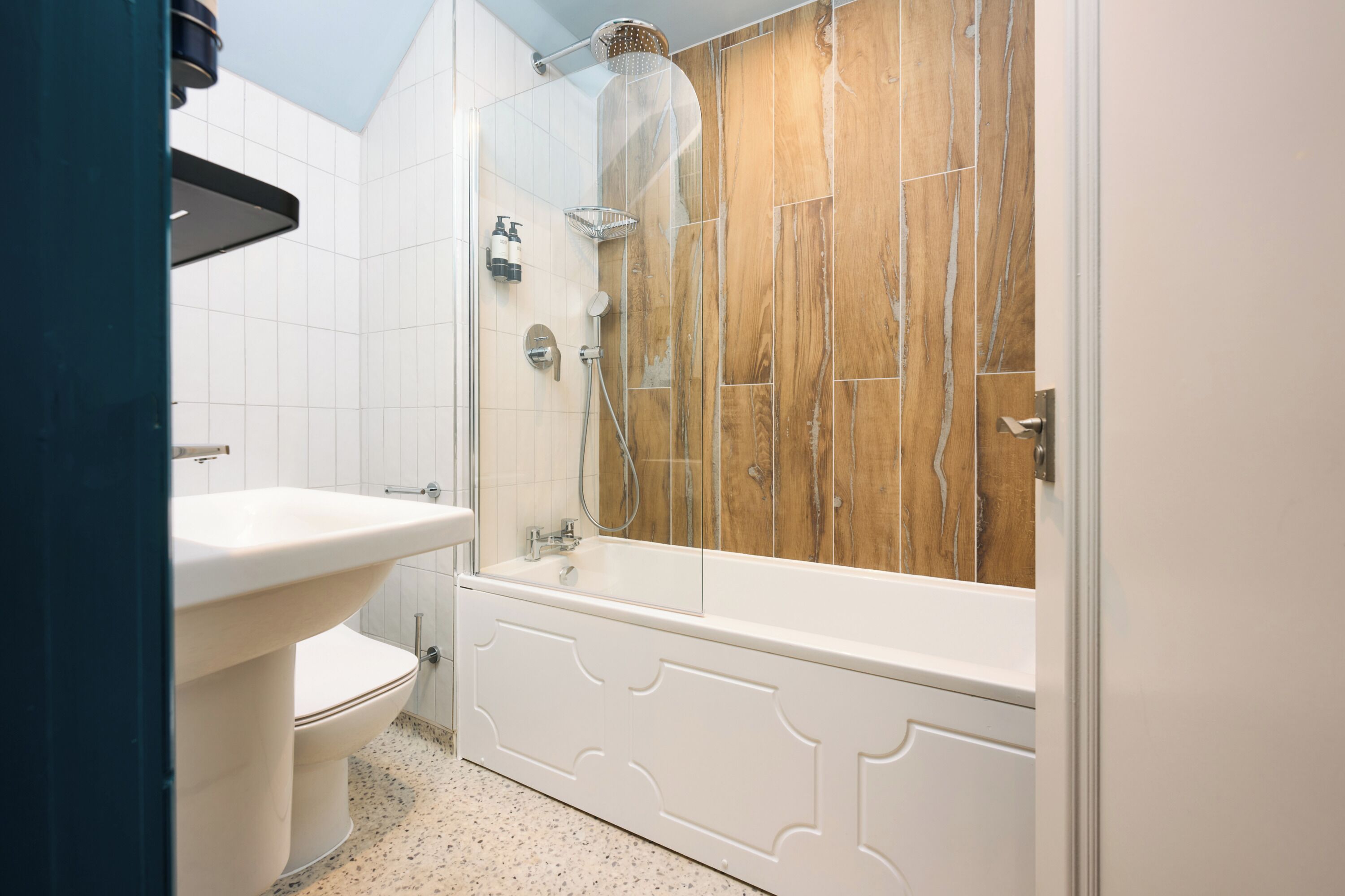 Une salle de bain avec des toilettes blanches, un lavabo blanc, une baignoire et un espace douche.