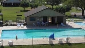 A swimming pool with lounge chairs and a small building with tables and chairs.
