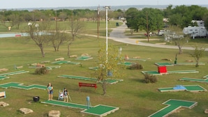 A miniature golf course with multiple green holes and red benches.