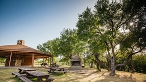 A covered picnic area with benches and a stone fireplace.
