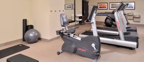 A gym with treadmills, an elliptical, a stationary bike, and exercise balls.