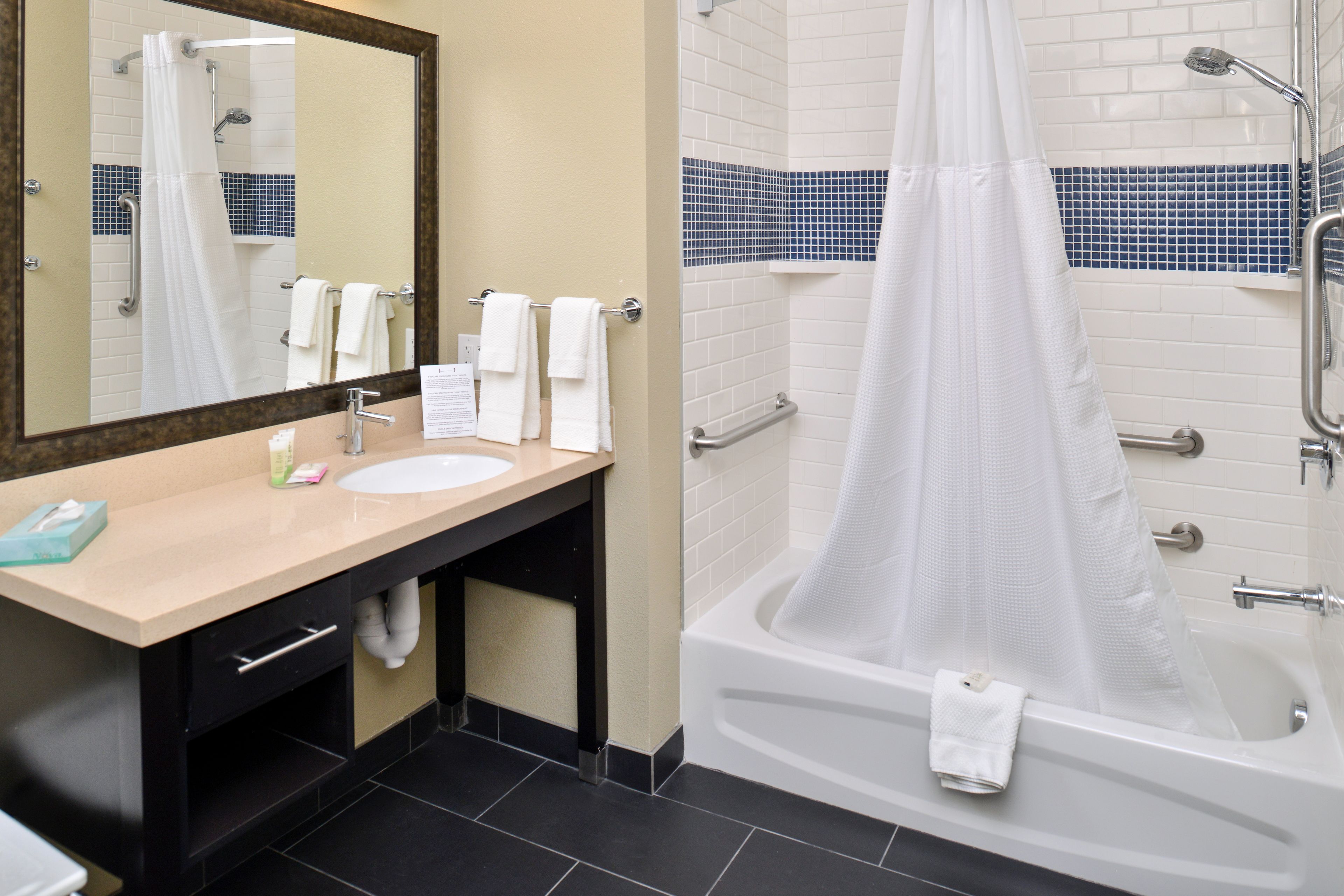 A bathroom with a sink, mirror, and bathtub.