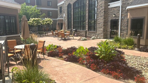 An outdoor patio area with stone walls, outdoor seating, and landscaped gardens.