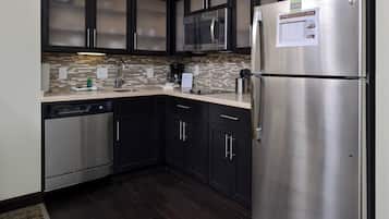 A modern kitchen with stainless steel appliances, dark cabinetry, and a tiled backsplash.
