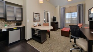 A compact hotel room with a kitchenette, a dining area, a seating area with a sofa and armchairs, and a large window with curtains. - Staybridge Suites Rochester - Commerce Dr NW by IHG (Rochester)