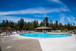 A swimming pool surrounded by lounge chairs and a covered pavilion.