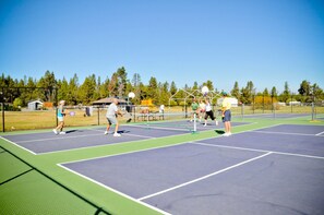 A tennis court with four players, a net, and a fence.