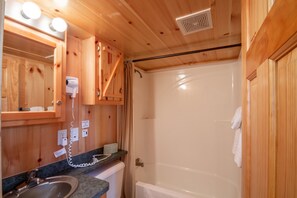 A wooden bathroom with a sink, mirror, and shower. - Blackhawk RV Campground (Milton)