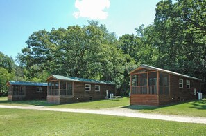 A rustic cabin-style lodging with a covered porch and a small outdoor seating area. - Blackhawk RV Campground (Milton)