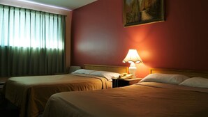 Una habitación de hotel con dos camas, una mesita de noche con lámpara y un cuadro en la pared.