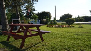 Una mesa de picnic en un césped, con un parterre de flores al fondo.