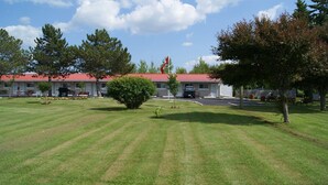 Un motel con techo rojo, un asta con bandera y un césped bien cuidado.