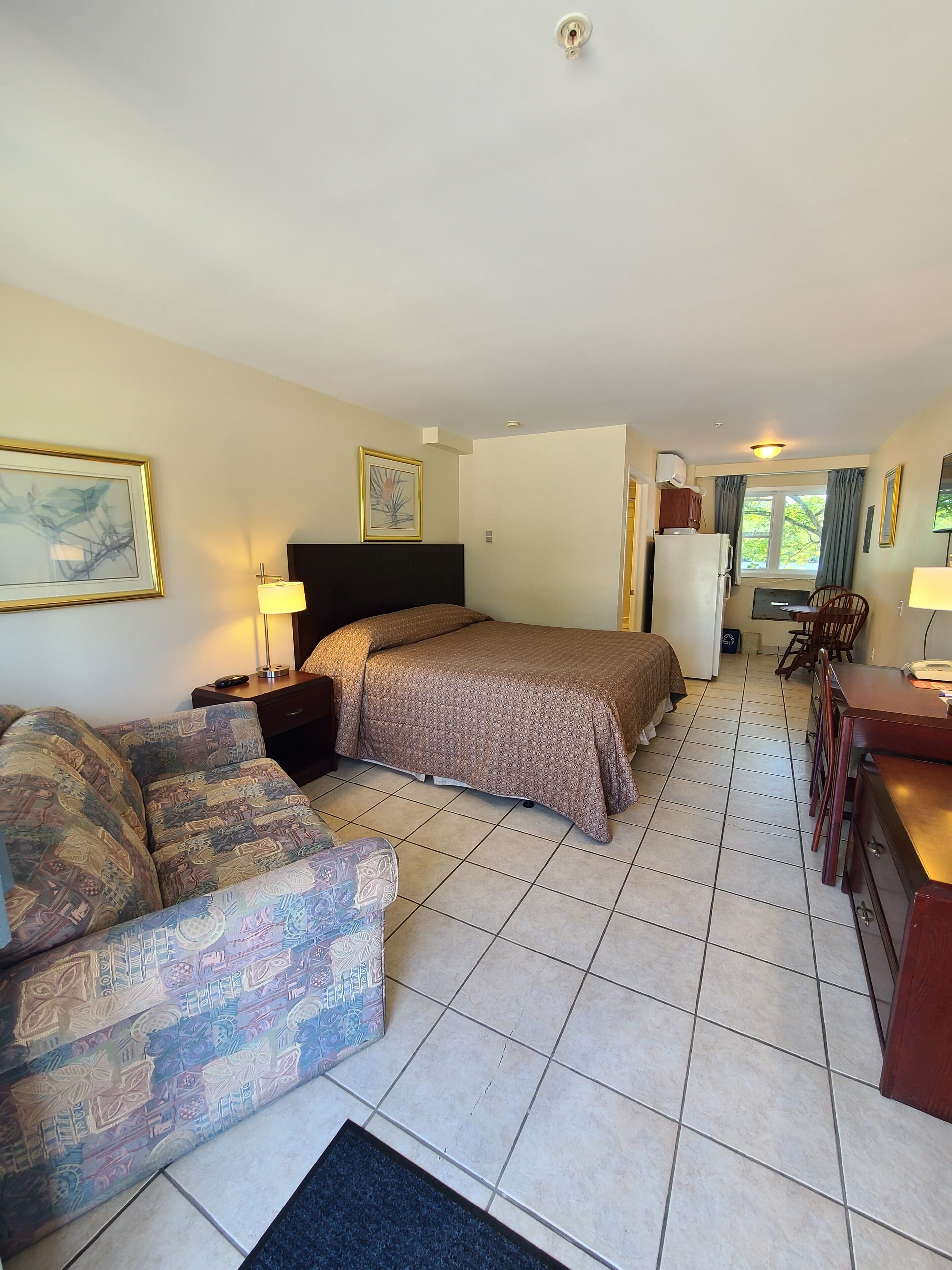 A hotel room with a bed, a sofa, a desk, and a chair.