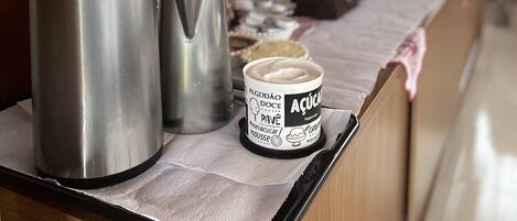 A stainless steel coffee maker and a thermos on a counter with a paper towel underneath. A jar of mousse is also visible.