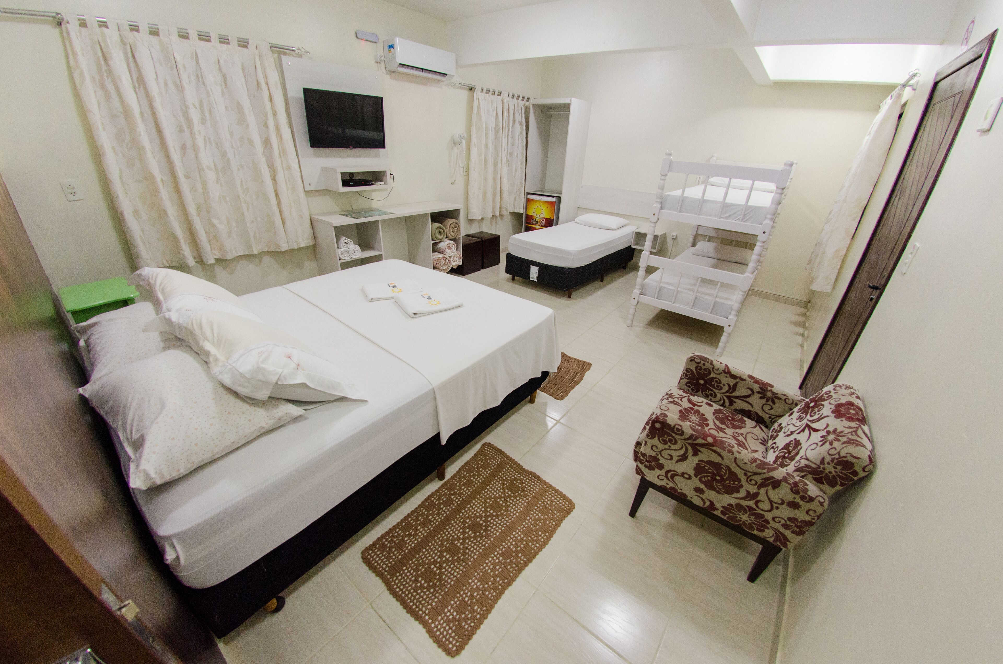 A hotel room with a single bed, a small desk, a chair, a mirror, and a bunk bed.