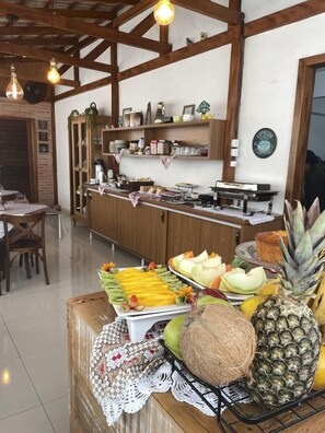 A cafe with a wooden counter, various food items, and a coffee machine. - Pousada Rota do Sol (Penha)