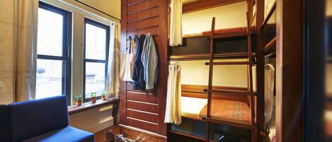 A compact room with a bunk bed, a sofa, a small table, and a window with curtains.